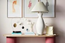 57 an eye-catching console table with pink fluted legs, a lamp with a fluted lampshade, some deco and a gallery wall