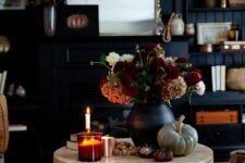 59 fall coffee table styling with pumpkins, a black vase with bold blooms, some candles and wooden beads is cool