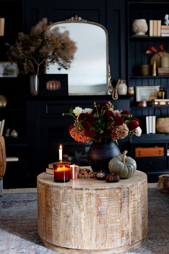 fall coffee table styling with pumpkins, a black vase with bold blooms, some candles and wooden beads is cool