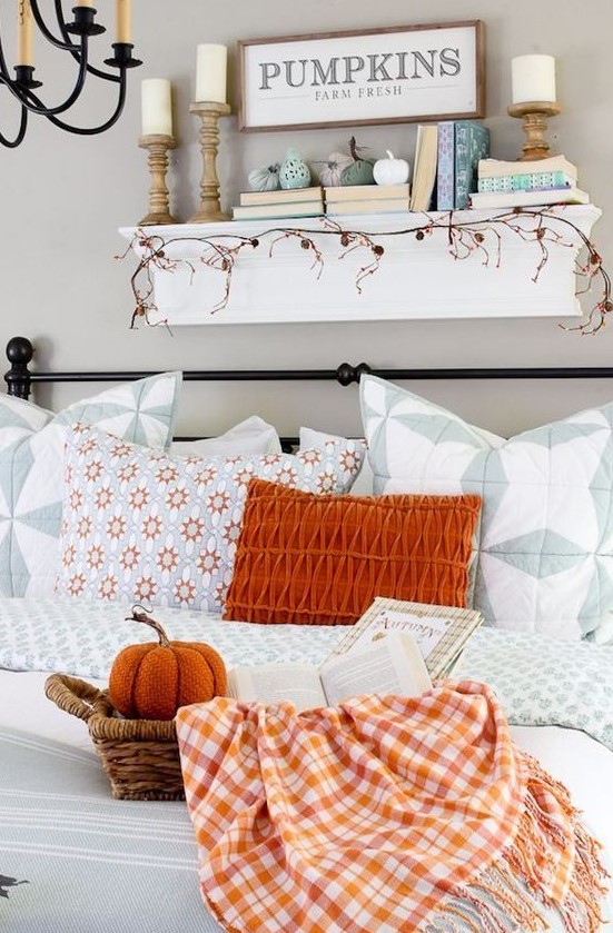a bold orange pillow, a plaid blanket and a fabric pumpkin in a basket for a fall touch in the living room