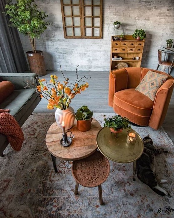 a rust-colored chair, blanket, bright coffee tables and bold orange blooms add fall coloring to the living room