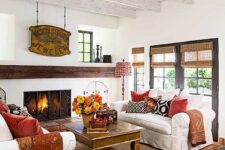 64 a traditional fall living room with a fireplace and a metal screen, white sofas, printed pillows, a vintage sign, bold flower and leaf arrangements to celebrate the fall