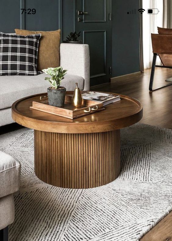 A modern stained coffee table with a round tray like tabletop and a fluted base is a lovely addition to a mid century modern space