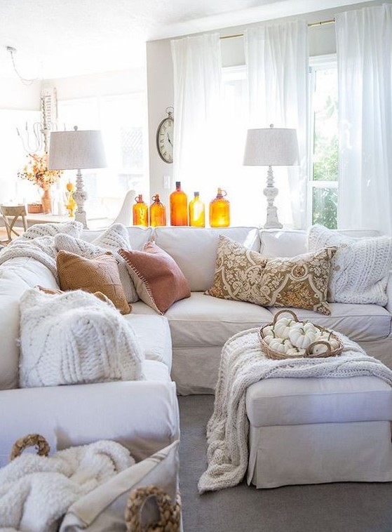 amber colored bottles and a basket with white pumpkins make this white living room more fall like