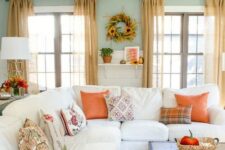 bright orange textiles, bright fall blooms and a sunflower wreath bring a fall feel to the neutral living room