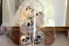 Halloween decor with books, a cloche with faux skulls and lights and spiderweb and a spider is easy to make