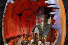 a Halloween diorama in a faux pumpkin, with a haunted house, skulls, a graveyard, some blackbirds is cool