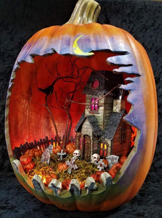 a Halloween diorama in a faux pumpkin, with a haunted house, skulls, a graveyard, some blackbirds is cool
