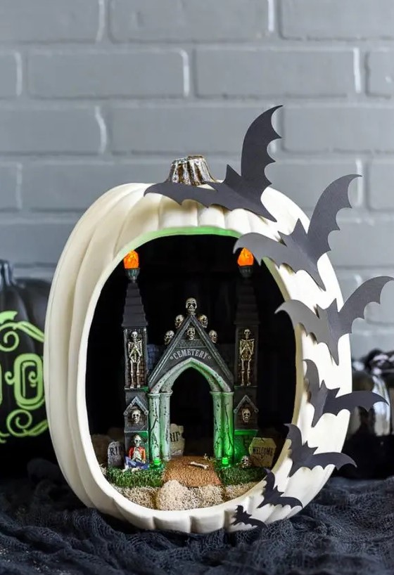 a Halloween diorama pumpkin with a castel, skeletons, lights and bats on one side is a hot idea that can be easily crafted