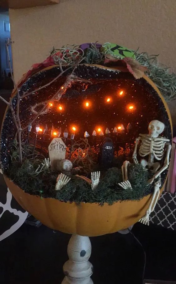 a Halloween pumpkin diorama with lights, skeletons, graveyards and branches and moss on the floor is a lovely idea