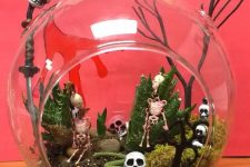 a Halloween terrarium with moss, faux succulents, skulls, skeletons, jack-o-lanterns and a snake is easy to make