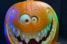 a beautiful and artful carved pumpkin with eyes and several rows of teeth is a bold decoraiton for Halloween