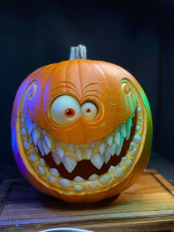a beautiful and artful carved pumpkin with eyes and several rows of teeth is a bold decoraiton for Halloween