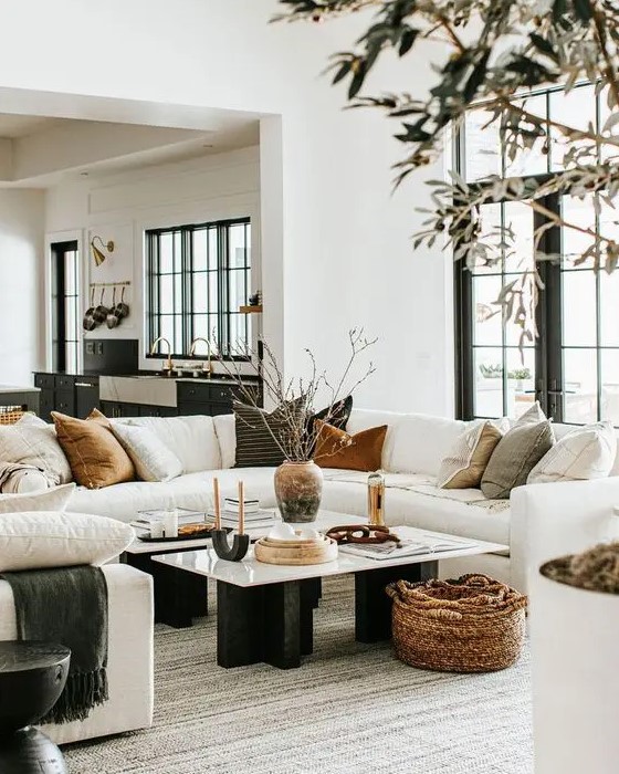 a beautiful modern farmhouse living room with a white sectional sofa, a couple of coffee tables, some side tables and a basket