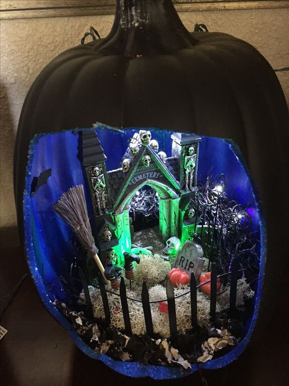 a black pumpkin with a blue inner, a green haunted house, skulls and skeletons, hay and lights
