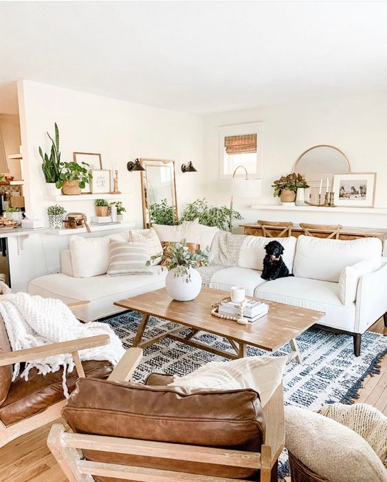 a boho meets modern farmhouse neutral living room with creamy seating furniture, brown leather chairs, a blue rug and a coffee table