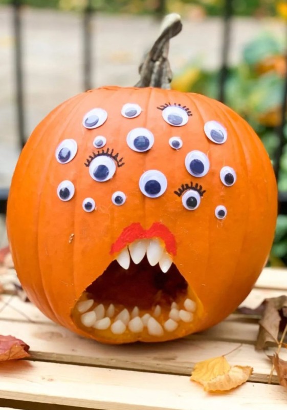 a carved pumpkin with teeth and googly eyes is an out of the box and spooky Halloween decoration