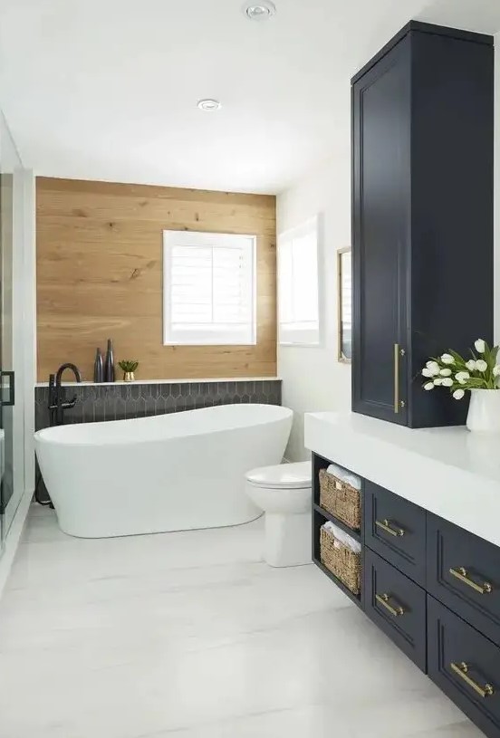 a chic modern country bathroom with a stained wood wall, a black tile accent, navy shaker style cabinets, white appliances and black fixtures