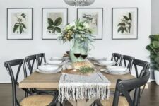 a chic modern country dining room with a stained table, black woven chairs, a wooden bead chandelier, a mini gallery wall