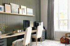 a chic modern farmhouse home office with a grene shiplap wall, a large double desk, neutral chairs and a black chandelier