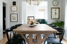 a chic modern farmhouse space with a stained trestle table, black chairs, potted greenery and some artwork, a gold pendant lamp