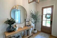 a classic modern farmhouse entryway with a console table, a round mirror, some baskets and vases plus a potted plant