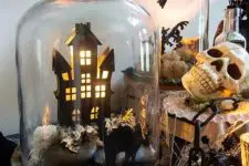 a cloche with a haunted house, a black cat, some rocks and moss is a cool idea for Halloween decor