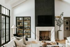 a contrasting modern farmhouse living room with a fireplace, built-in storage units, neutral seating furniture and a low coffee table