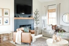 a cozy modern farmhouse living room with a fireplace clad with navy shiplap, neutral seating furniture, an amber leather chair and a coffee table
