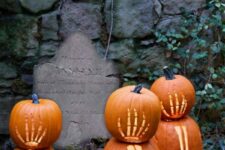 a create an outdoor graveyard in your garden and style it with tombstones and skeleton hand pumpkins