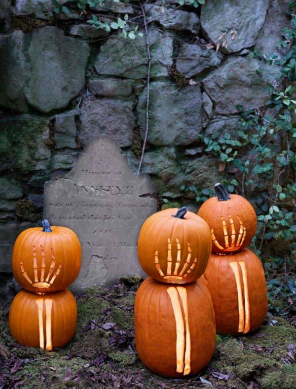 a create an outdoor graveyard in your garden and style it with tombstones and skeleton hand pumpkins