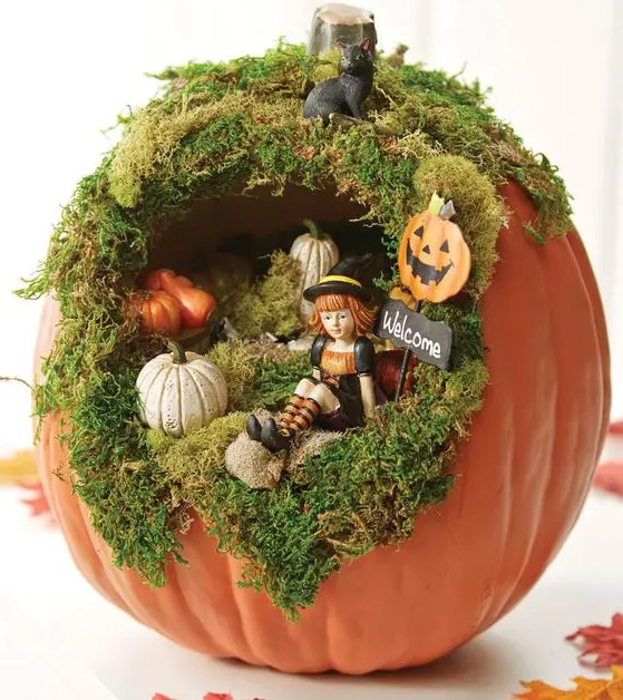 a cute Halloween diorama with moss, small pumpkins, a little witch and a black cat on top is a very fun solution for a kids' party