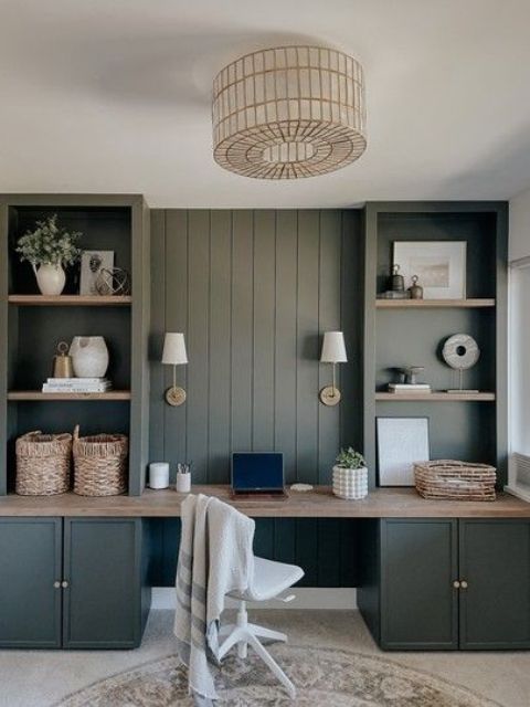 a dark green home office in farmhouse style, with built-in cabinets, a white chair and baskets for decor