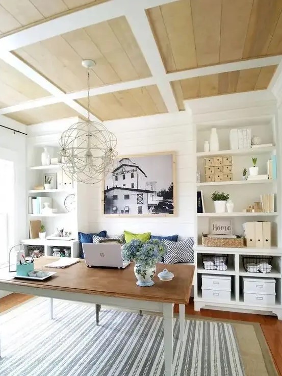 a farmhouse home office with built-in storage units, a simple desk and a built-in bench to sit on, a sphere chandelier
