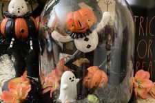 a funny Halloween cloche with moss, leaves, funny figurines and jack-o-lanterns is amazing for stylign your space