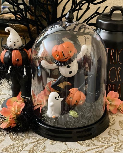 A funny Halloween cloche with moss, leaves, funny figurines and jack o lanterns is amazing for stylign your space