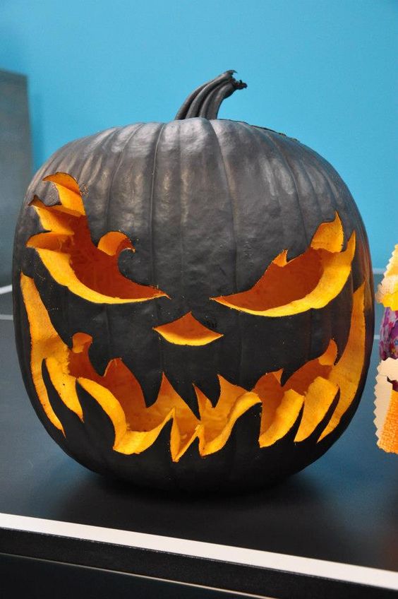 a gorgeous matte black pumpkin with carved eyes and teeth is a catchy solution for Halloween
