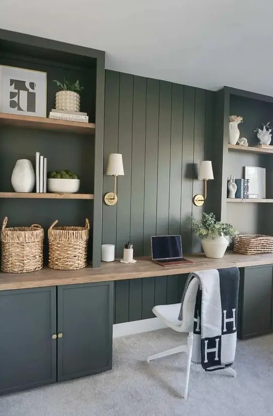 a green modern farmhouse home office with shiplap walls and storage units, a butcherblock countertop, sconces and greenery
