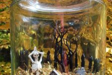 a jar with moss, a skeleton and a mini graveyard, a fence and a mini tree is a lovely Halloween terrarium