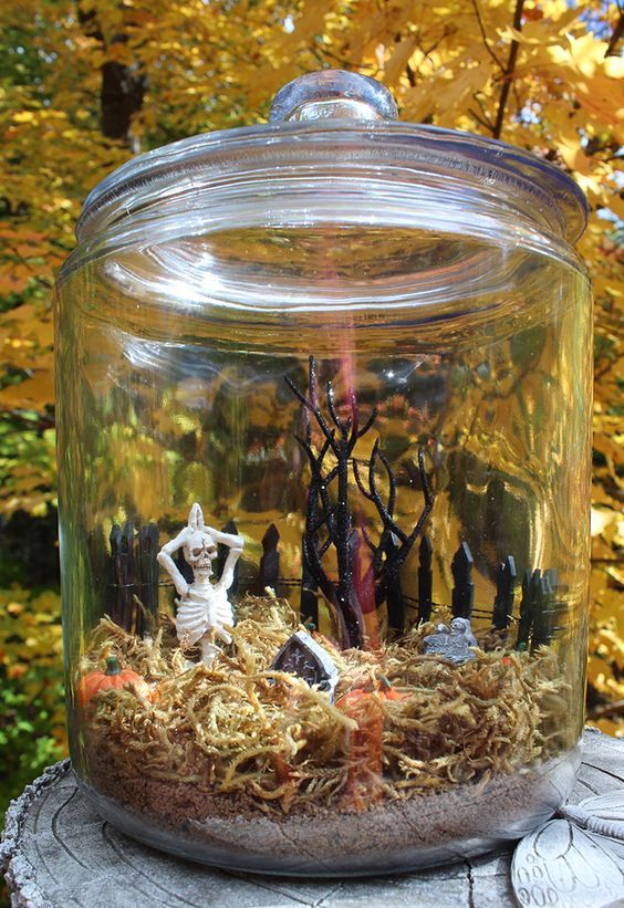 a jar with moss, a skeleton and a mini graveyard, a fence and a mini tree is a lovely Halloween terrarium