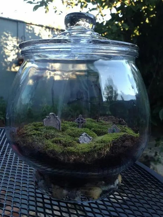 a jar with moss and a mini graveyard is a beautiful and realistic decoration for Halloween