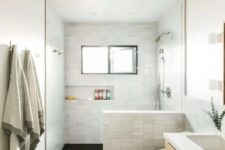 a laconic modern farmhouse bathroom with a black floor and marble tile walls, a timber vanity, a shower space and a window