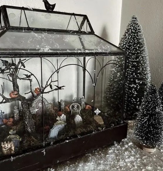 a large Halloween terrarium, a cemetarrium with a tree with jack o lanterns, tombstones, moss is a cool and bold decoration