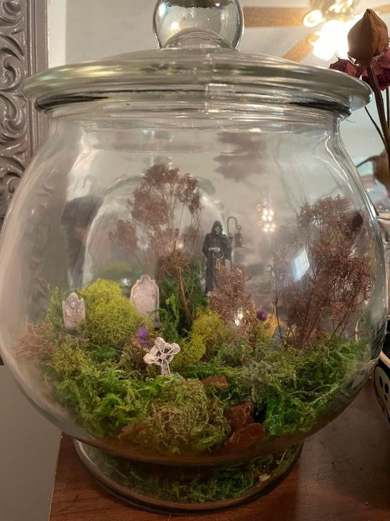 a large jar with moss, tombstones, crosses, Death and some mini trees is a lovely Halloween terrarium
