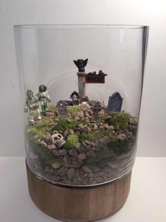 a large jar with pebbles and moss, zombies and skulls and some tombstones is a cool solution for Halloween