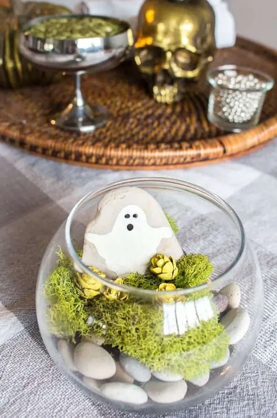 a last-minute Halloween terrarium with pebbles, moss, pinecones, a rock with a ghost is a simple and lovely idea for a kids' party