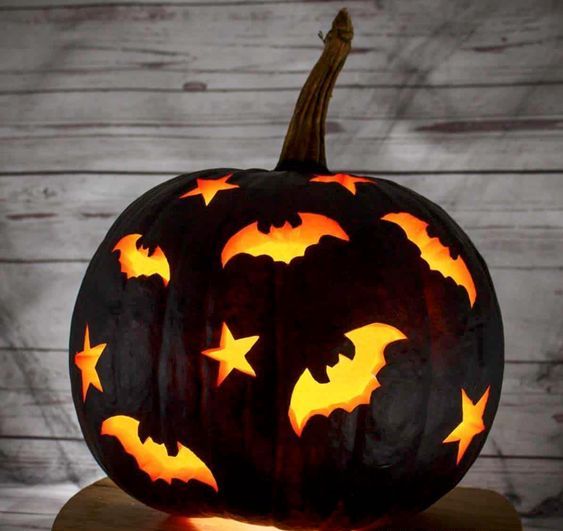 a matte black Halloween pumpkin with carved stars and bats is a cool way to illuminate the space
