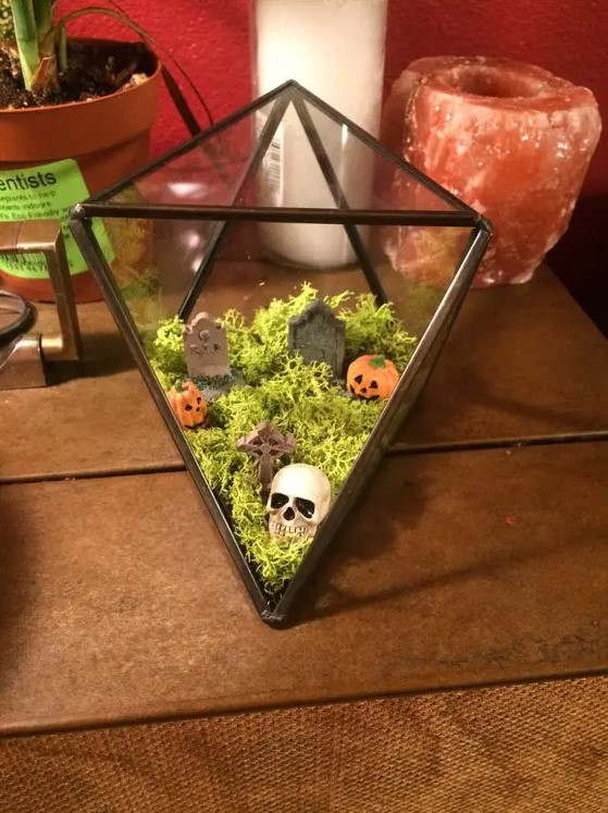 a mini Halloween cemetarium with moss, mini pumpkins, tombstones and a skull is an easy to repeat solution