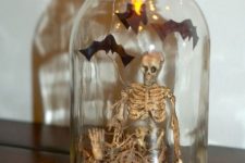 a mini Halloween terrarium with hay, a skeleton, bats and lights is a cool solution to rock, you can make it easily