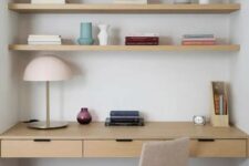 a minimalist niche with built-in shelves and a desk with drawers, a neutral chair, a table lamp and some books